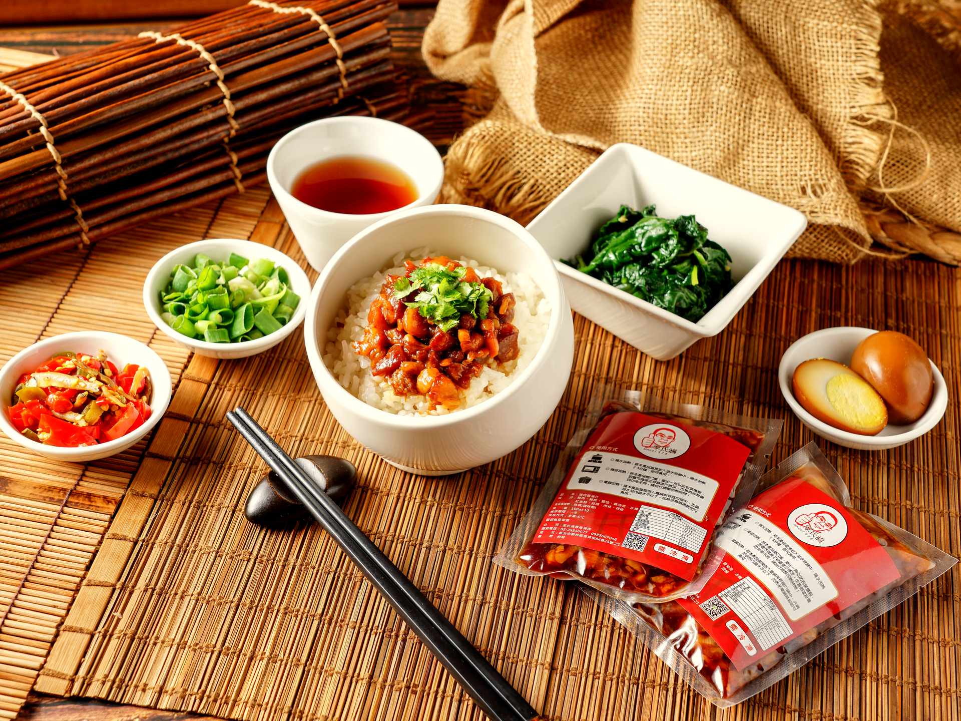 竹簾上擺盤完成的滷肉飯套餐與家氏滷商用包裝